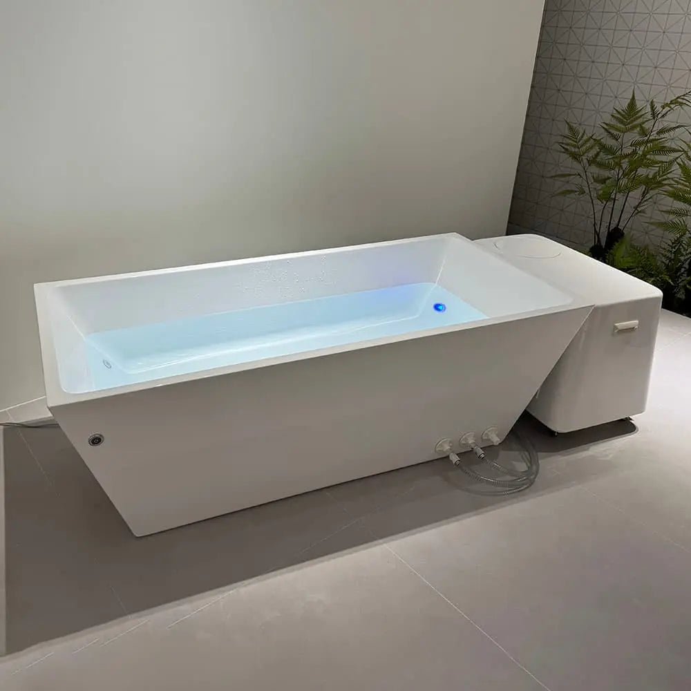 The Deluxe Plunge by Lunara, a sleek rectangular white cold plunge with advanced cooling system, handles, and visible hoses, sits in a minimalist bathroom with geometric tiles and plants—perfect for home recovery.